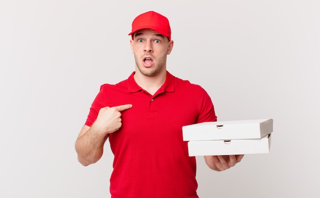 Pizza consegna uomo che sembra scioccato e sorpreso con la bocca spalancata, indicando se stesso