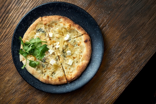 Pizza cotta a legna con 4 tipi di formaggio e besciamella su fondo di legno. pizzette una specie di pizza italiana