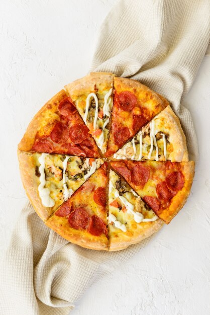 Pizza da pezzi diversi su un asciugamano di lino. Orientamento verticale, vista dall'alto, disposizione piatta.