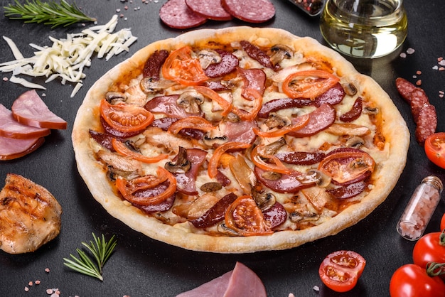 Pizza deliziosa fresca fatta in un forno con focolare con salsiccia, pepe e pomodori. Cucina mediterranea