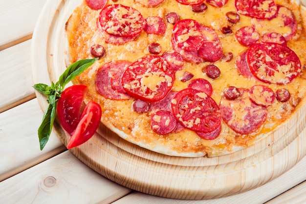 Pizza di carne con pomodori sul tavolo di legno