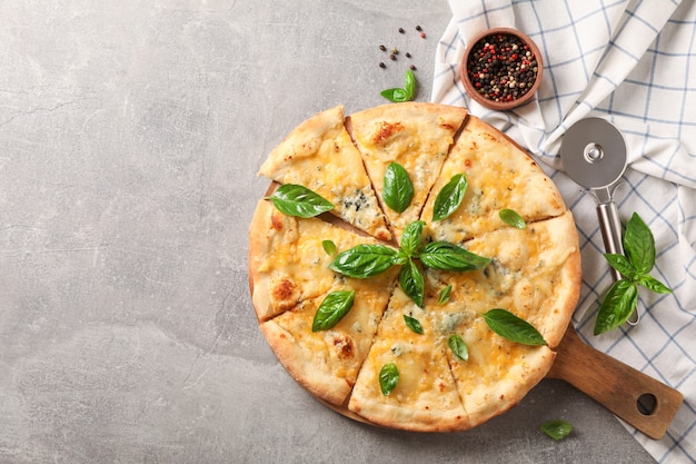 Pizza di formaggio con basilico, taglierina e spezie su sfondo grigio