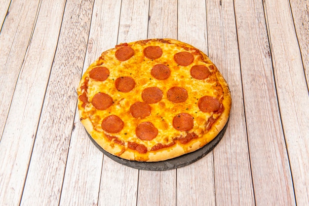 Pizza diavola piccante in stile italiano con peperoni su piatto di ardesia nera