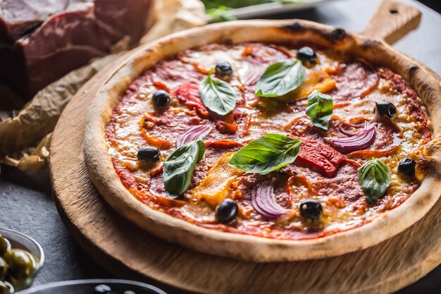 Pizza diavolo italiano tradizionale pasto da salame piccante peperoni peperoncino cipolla olive e basilico.