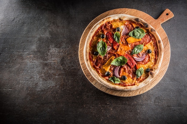 Pizza diavolo italiano tradizionale pasto da salame piccante peperoni peperoncino cipolla olive e basilico.