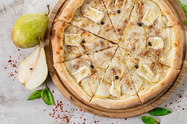 Pizza dolce con formaggio brie alla pera sullo sfondo di cemento