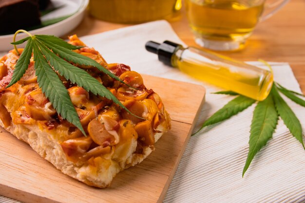 Pizza fatta in casa con foglia di marijuana o cannabis su vassoio in legno.