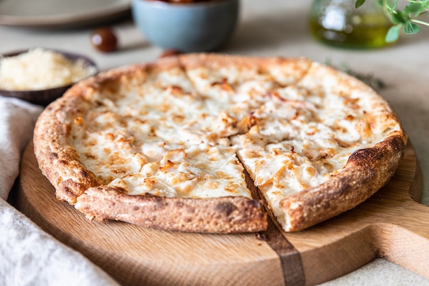 Pizza fatta in casa con pollo e formaggio su superficie di cemento chiaro in salsa bianca