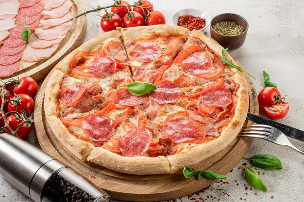 Pizza fresca con carne e prosciutto sullo sfondo di cemento