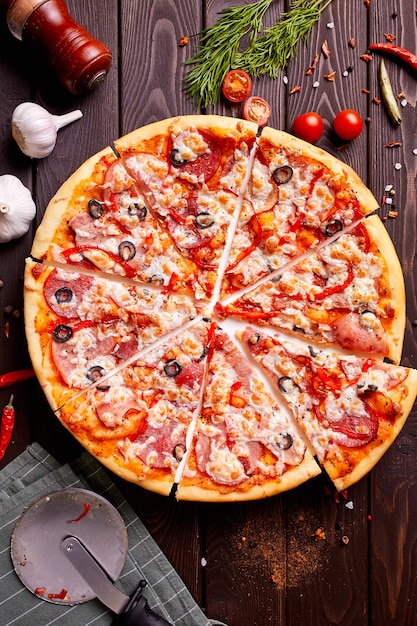 Pizza fresca con i pomodori, il formaggio ed i funghi sul primo piano di legno della tavola.