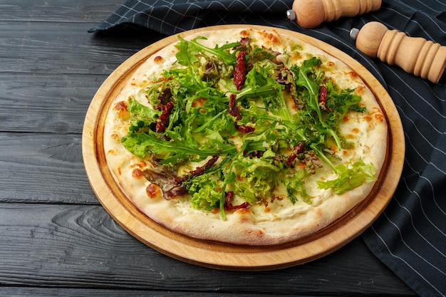 Pizza fresca e gustosa su uno sfondo di legno nero da vicino