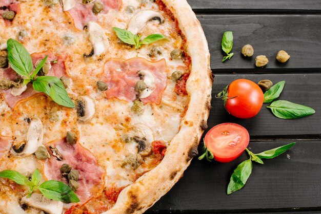 Pizza fresca gustosa con ingredienti su fondo di legno