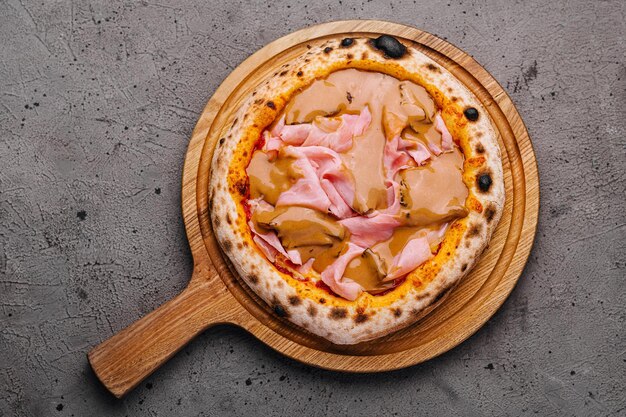 Pizza gourmet italiana con prosciutto su tavola di legno