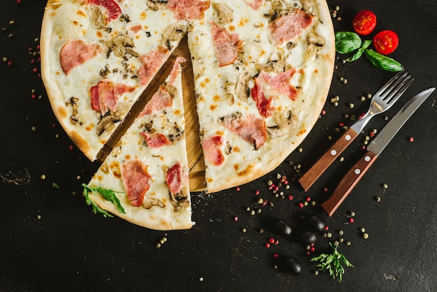 Pizza gustosa di carne con vari ingredienti su sfondo nero