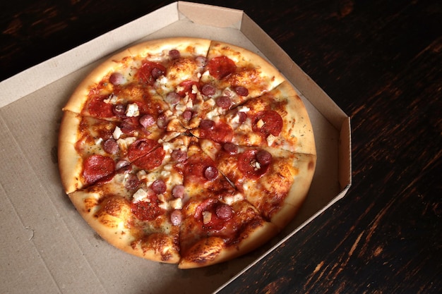 Pizza in una scatola di cartone su uno sfondo scuro Vista dall'alto Consegna della pizza