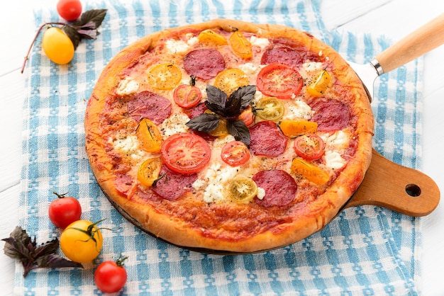 Pizza italiana ai peperoni con salame e formaggio su fondo bianco in legno rustico