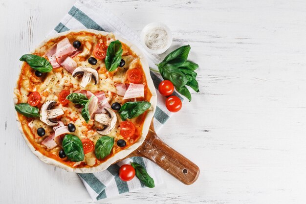 Pizza italiana con funghi, peperoni, basilico, pomodoro, olive e formaggio