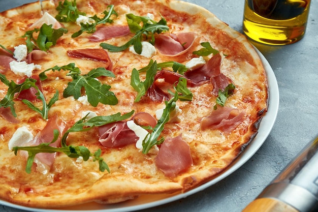 Pizza italiana con jamon, rucola e crema di formaggio su un grigio