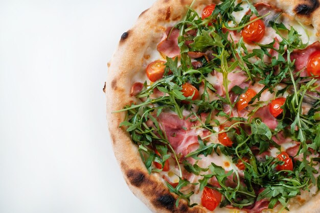 Pizza italiana con prosciutto rucola e pomodori primo piano Consegna italiana di fast food