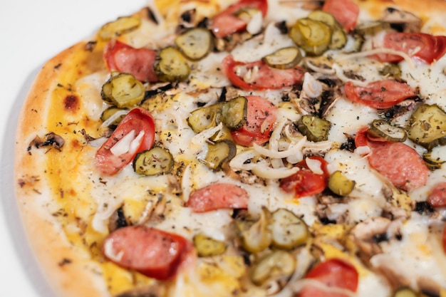 Pizza italiana con salsiccia funghi cipolle e cetrioli sottaceto vista laterale