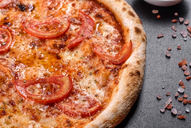 Pizza italiana deliziosa fresca con funghi e pomodori su uno sfondo di cemento scuro. cucina italiana