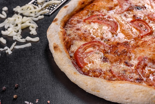 Pizza italiana deliziosa fresca con funghi e pomodori su uno sfondo di cemento scuro. cucina italiana