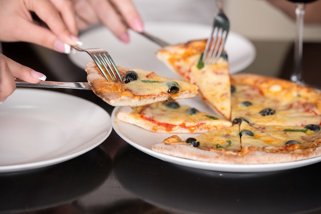 Pizza italiana delle olive e del formaggio del primo piano con la forcella e la lama