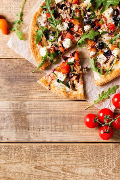 Pizza italiana di verdure con pomodori su sfondo wodeen, copia spazio, vista dall'alto, verticale