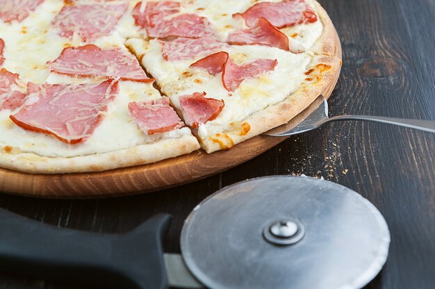 Pizza italiana fresca e deliziosa su un tavolo di legno e un coltello da pizza