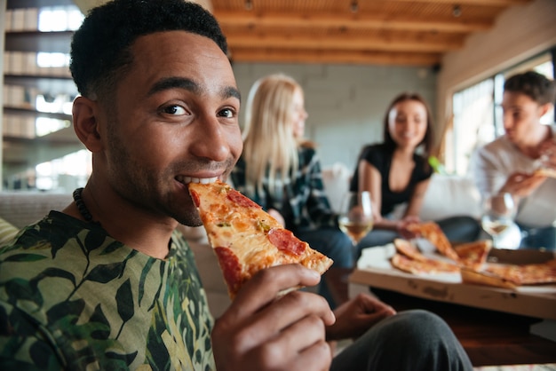 Pizza mangiatrice di uomini africana circondata dagli amici