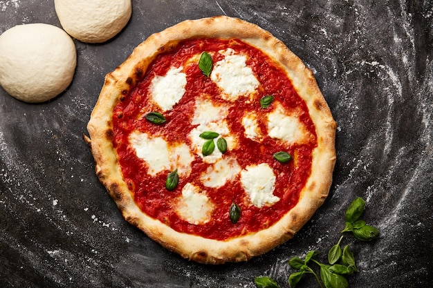 Pizza Margherita con pasta isolata su uno sfondo scuro con cibo crudo vista superiore di un aperitivo fast food italiano