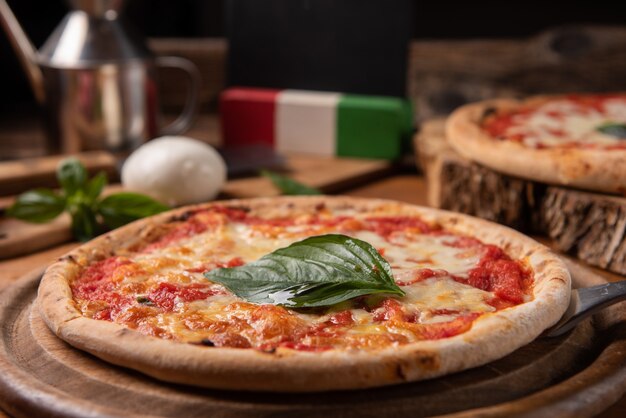 Pizza Margherita condita con foglie di basilico fresco su tavola rustica