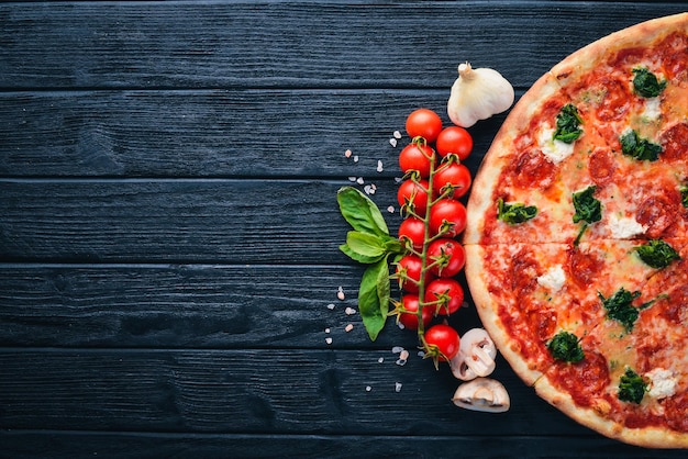 Pizza Napoletana Spinaci gorgonzola formaggio salsiccia salame Su uno sfondo di legno Vista dall'alto