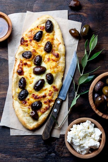 Pizza ovale fatta in casa con olive intere e formaggio