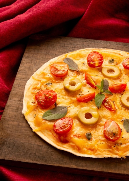 Pizza pan fatta in casa con pomodori, basilico e olive in un piatto di legno in vista dall'alto