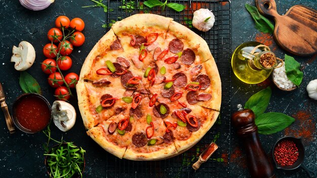 Pizza piccante con salsicce e peperoncino su sfondo di pietra nera Spazio libero per il testo