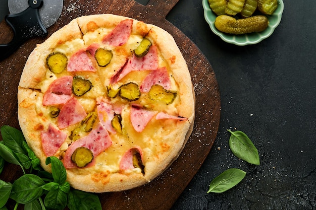 Pizza Pizza tradizionale al bacon con prosciutto, funghi, cetriolo sottaceto, formaggio e ingredienti da cucina, pomodori, basilico, su sfondi di tavolo in legno, cibo tradizionale italiano, vista dall'alto, modello