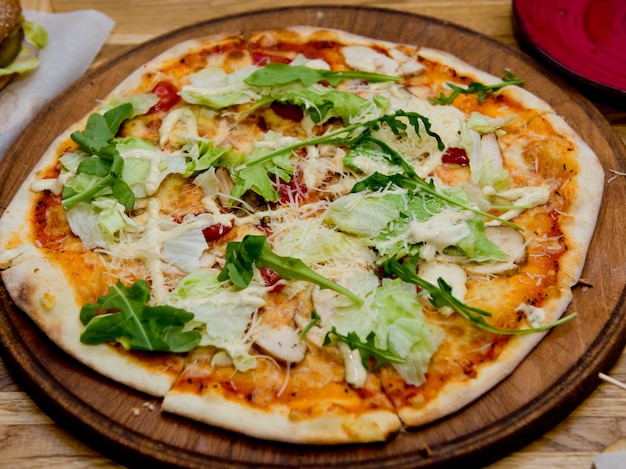 Pizza pronta su un piatto di legno. Messa a fuoco selettiva.