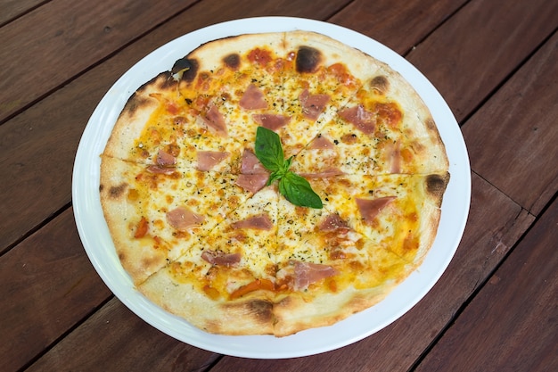 Pizza Prosciutto di Parma in bianco piatto sul tavolo di legno