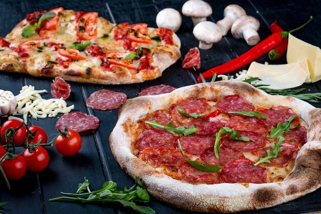 Pizza romana e napoletana su fondo scuro con ingredienti