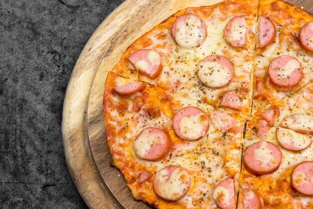 Pizza salsiccia sul piatto di legno