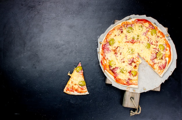 Pizza saporita con le spezie e le olive sul nero