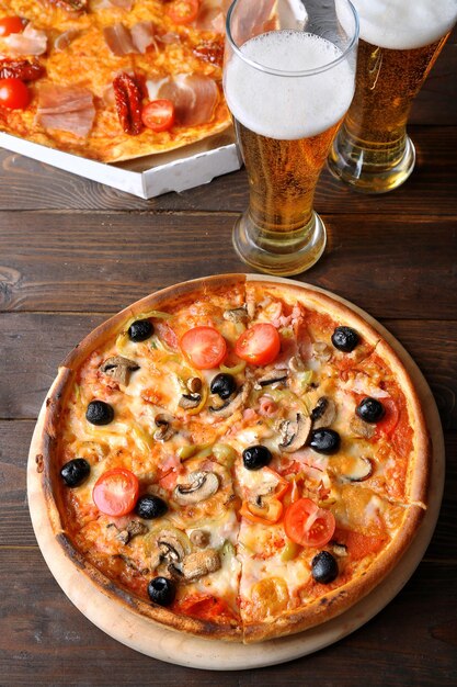 Pizza servita con birra sulla tavola di legno