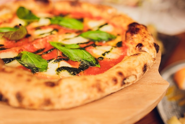 Pizza sottile condita con foglie di basilico fresco Fette di pizza Cibo fatto in casa Pizza vegetariana italiana Concetto per un pasto gustoso e abbondante Fondo rustico in legno