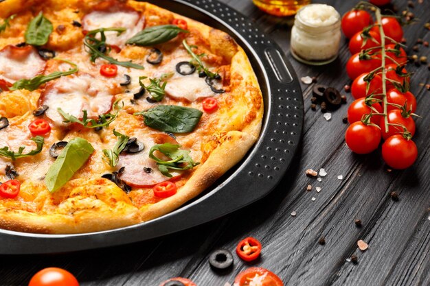 Pizza su un piatto nero su uno sfondo di legno scuro