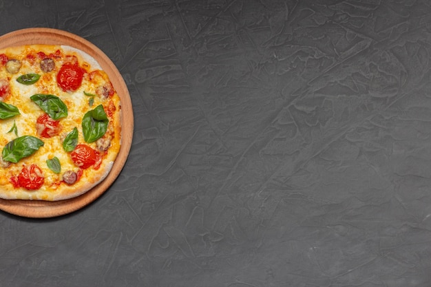 Pizza sul piatto di legno su sfondo di pietra nera Pizza al formaggio con pomodoro mozzarella e basilico