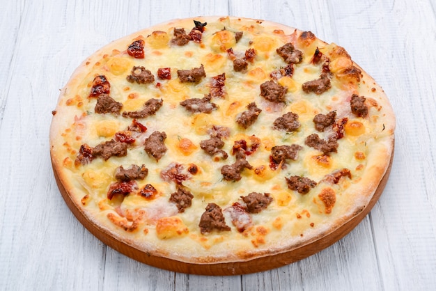 Pizza tritata della cipolla rossa del pomodoro della carne su una tonalità di superficie di legno