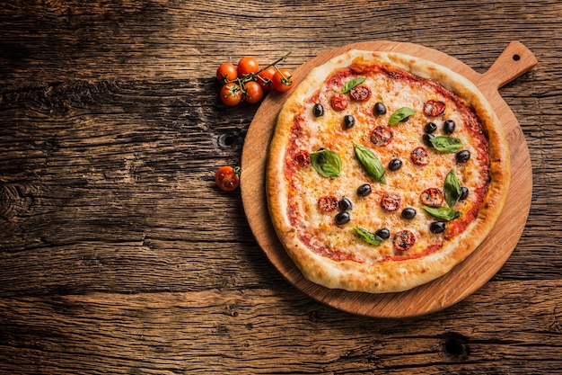 Pizza. Una gustosa pizza italiana fresca servita su un vecchio tavolo di legno.