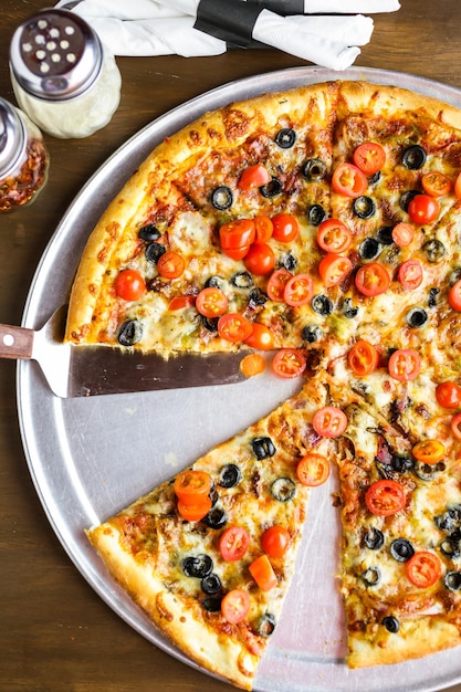 Pizza vegetariana con olive e pomodorini sul tavolo.