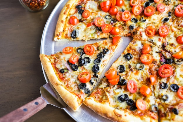 Pizza vegetariana con olive e pomodorini sul tavolo.